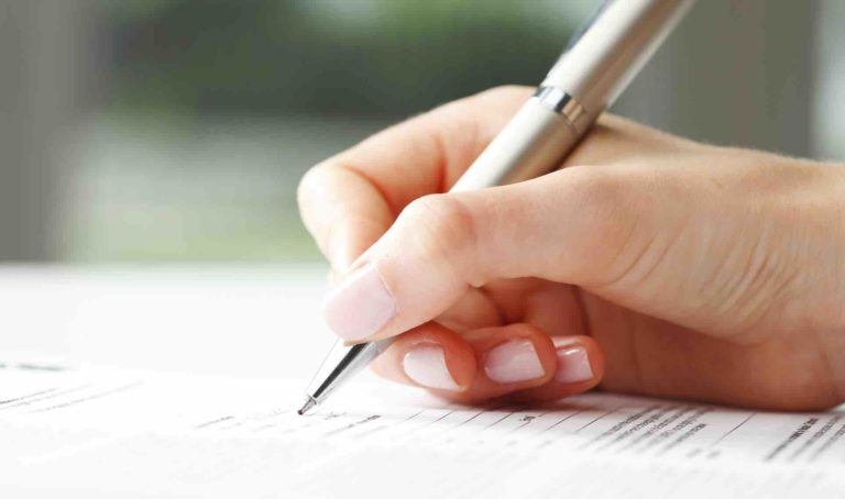 Frauenhand hält Stift und füllt Formular aus