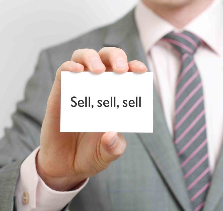 Mann hält Schild mit sell darauf.