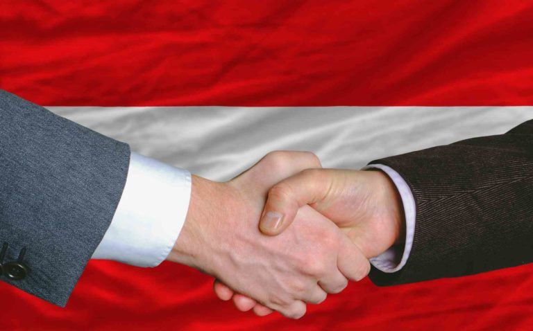 Hände schütteln vor österreichischer Fahne