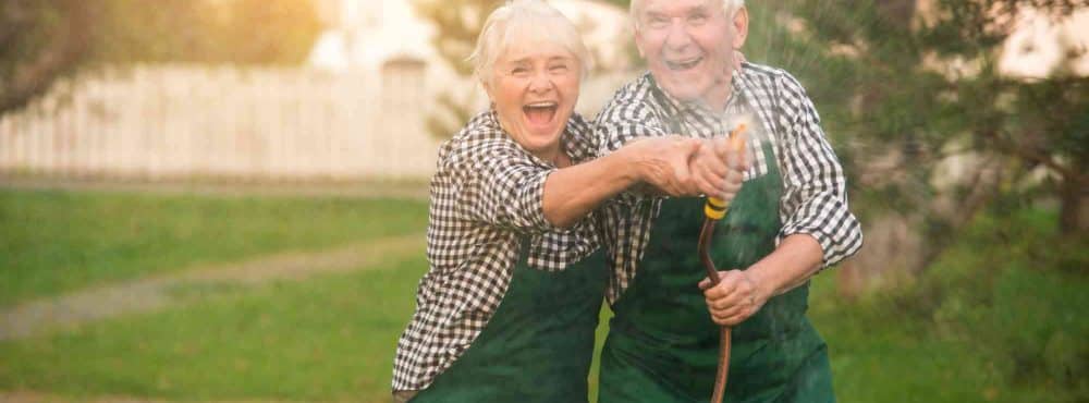Älteres Ehepaar hat Spaß beim Gießen am Hof