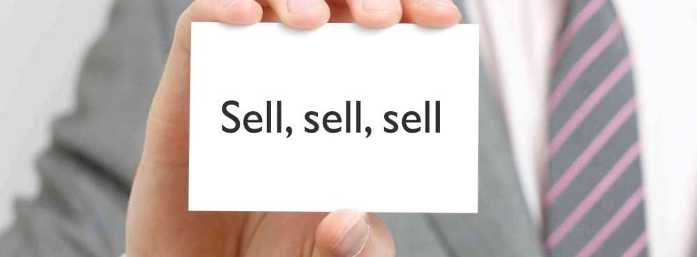 Mann hält Schild mit sell darauf.